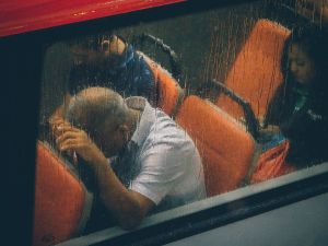 passengers on a bus seen through windows streaked with rain