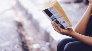 Close-up of a hand holding a book whilst a person is reading