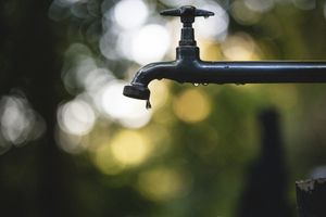 Tilt shift lens photography of black steel faucet dripping water