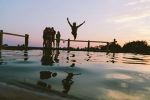 Man in mid-air jumping into a body of water