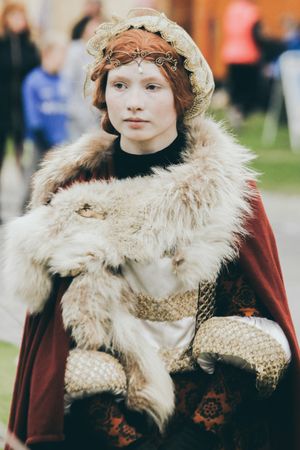 Woman in historical costume of Elizabethan England, wearing red and white fur coat